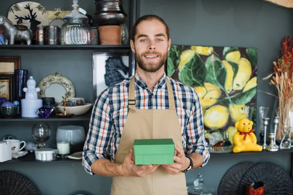 Homme souriant posant au magasin de décoration avec boîte verte dans les mains — Photo