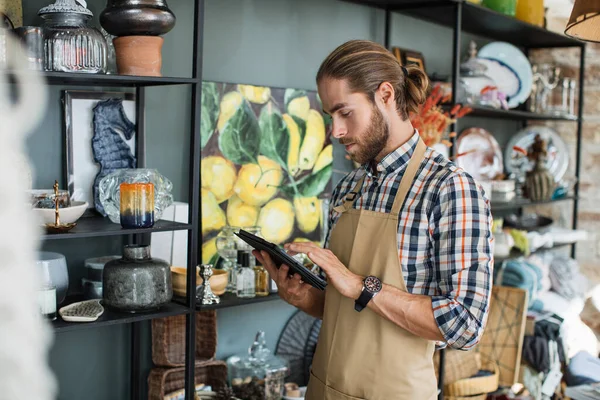 Hombre usando la tableta para hacer catálogo en línea de la tienda de decoración —  Fotos de Stock