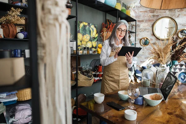 Vendeuse avec tablette racontant des marchandises au magasin de décoration — Photo