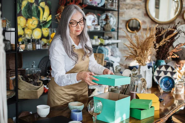 Aged woman doing inventory at decor store — Stock Photo, Image