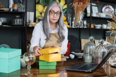 Mağazada dizüstü bilgisayar kullanan yaşlı bir kadın.