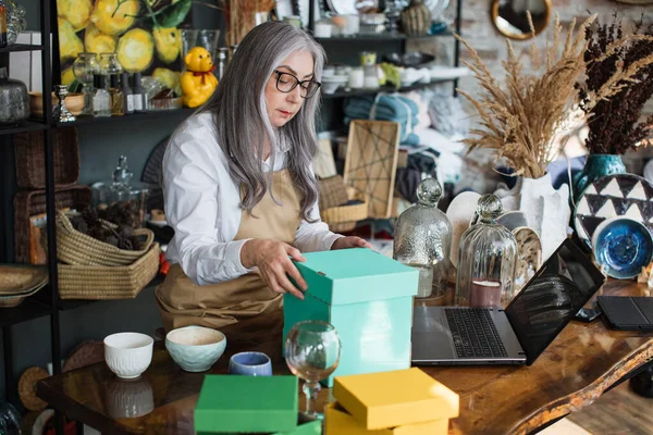 Aged woman doing inventory at decor store — Stock Photo, Image