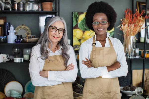 Diverse saleswomen smiling and standing with arms crossed at decor store — Stock Photo, Image