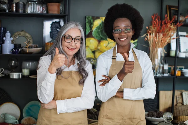 Diverse saleswomen smiling and showing thumbs up at store — Stock Photo, Image