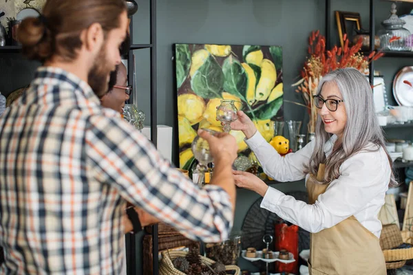 Mature saleswoman showing goods at store for customers