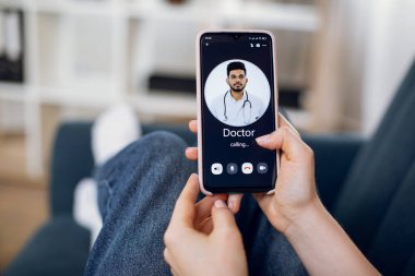 Hasta kadın ellerinin yakın plan görüntüsü, akıllı telefon kullanması ve doktorunu araması, genç Hintli adam. Uzaktan tıbbi servis uygulaması