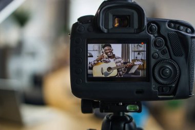 Neşeli adam gitar çalarken kameraya video kaydediyor