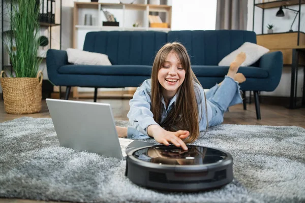 Happy woman using robot vacuum cleaner for chores — Stock Photo, Image