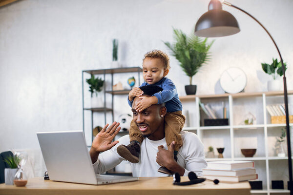 Afro american father with baby son working from home
