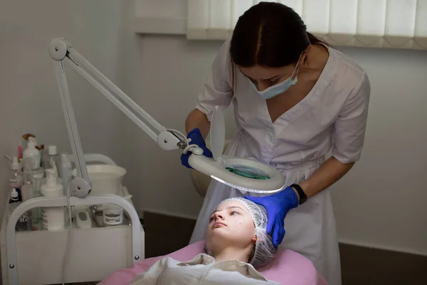 현대 미용실에서 일하는 미용사 의사. 십 대 소녀에게 피부 치료를 하도록 준비시키고 있는 젊은 여성 전문 유방 전문의의 모습. — 스톡 사진