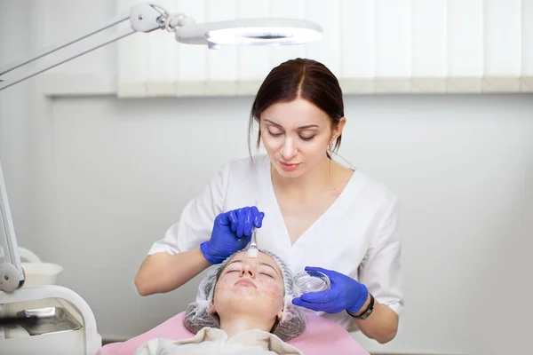 Concepto de tratamiento facial. Vista frontal del médico profesional de la mujer, por lo que el procedimiento de tratamiento de la piel para la joven adolescente con acné en la clínica moderna. —  Fotos de Stock