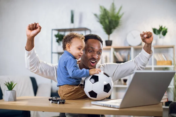 Joven padre e hijo pequeño viendo el partido de fútbol en el ordenador portátil — Foto de Stock