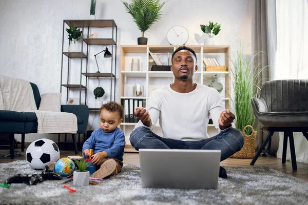 Negro hombre trabajando en portátil y jugando con hijo — Foto de Stock