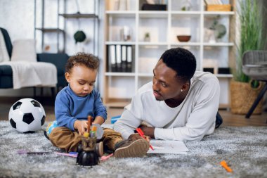 Afro-Amerikan baba ve oğul yere kalem çiziyorlar.