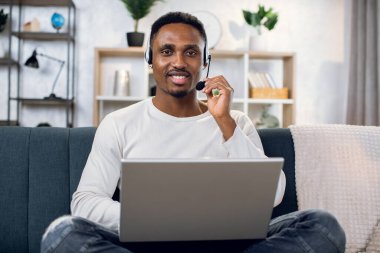 Afrikalı adam uzaktan çalışma için kulaklık ve dizüstü bilgisayar kullanıyor
