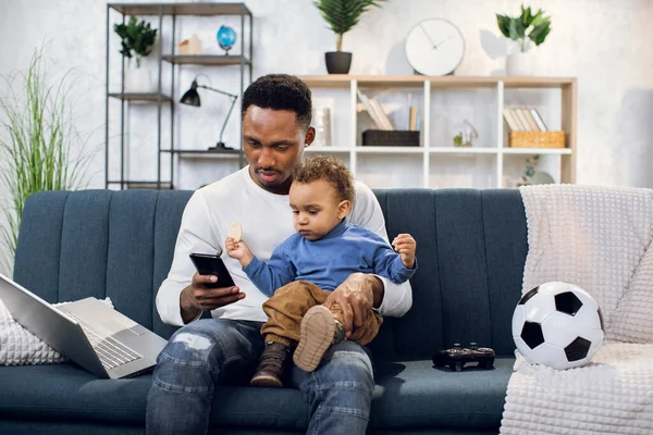 Pai e filho usando smartphone enquanto sentado no sofá — Fotografia de Stock