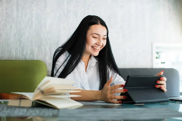 Feliz alegre simpática mulher asiática usa tablet digital, enquanto se senta à mesa no café. Jovem empresária tendo videochamada, sorrindo alegremente para webcâmera. — Fotografia de Stock