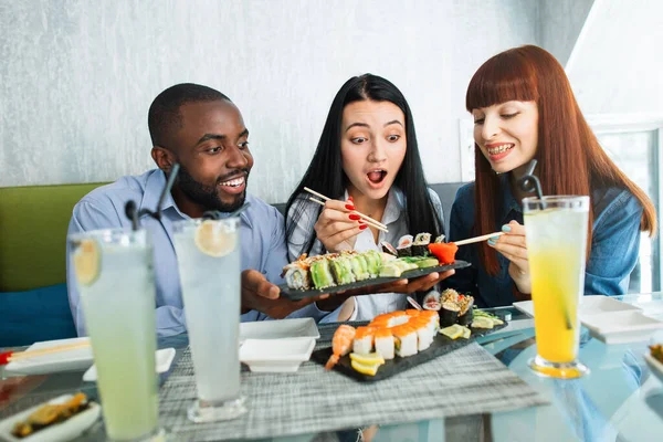 친구들 과 함께 보내는 시간. 젊은 사람들은 현대 식당에서 맛있는 초밥을 먹으면서 다 윤리적 인 사람들, 아프리카 사람들 과 아시아 사람들 및 코카서스 여자들을 흥분시켰다. — 스톡 사진
