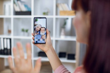 Büyükannesi ve büyükbabasıyla video görüşmesi için akıllı telefon kullanan bir kadın.