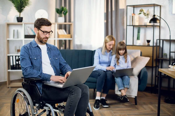 Gehandicapte man met behulp van aptop terwijl vrouw en kind zitten op de bank — Stockfoto