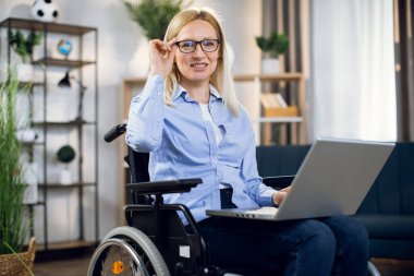 Özürlü bir kadın evde dizüstü bilgisayarla çalışıyor.