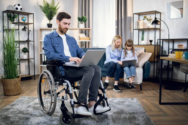 Homem com deficiência e sua família usando laptops em casa — Fotografia de Stock