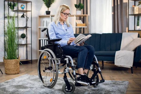 Όμορφη γυναίκα κάθεται σε αναπηρική καρέκλα και το βιβλίο ανάγνωσης — Φωτογραφία Αρχείου