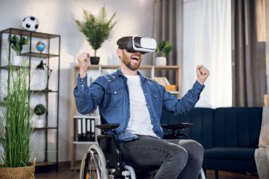 Tekerlekli sandalyede oturan ve VR gözlükleriyle oyun oynayan adam.