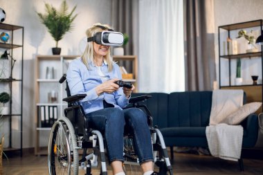 Tekerlekli sandalyedeki kadın 3 boyutlu gözlüklerle sanal oyunlar oynuyor.
