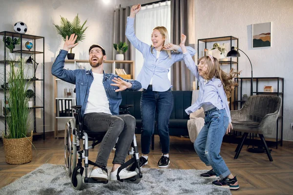 Mujer en silla de ruedas bailando con marido e hija — Foto de Stock
