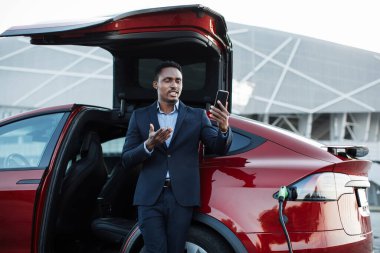 Otomatik şarj edilirken görüntülü arama için cep telefonu kullanan adam