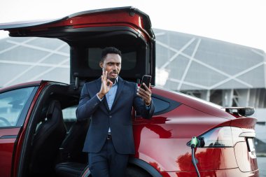 Otomatik şarj edilirken görüntülü arama için cep telefonu kullanan adam