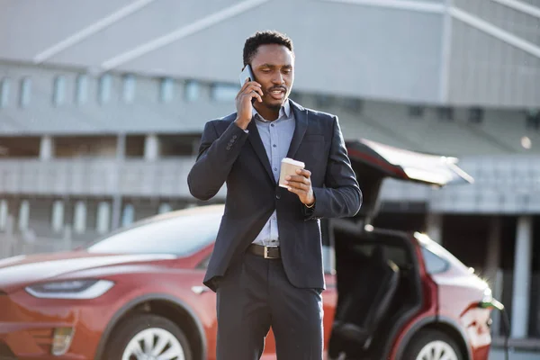 Hombre teniendo charla móvil mientras espera coche eléctrico — Foto de Stock