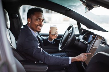 İşadamı elektrikli arabasının dokunmatik ekranında GPS uygulaması kullanıyor.