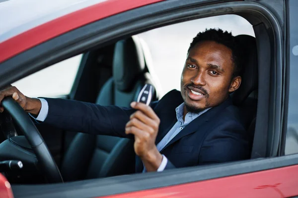Orang Afrika duduk di mobil listrik baru dengan kunci di tangan — Stok Foto