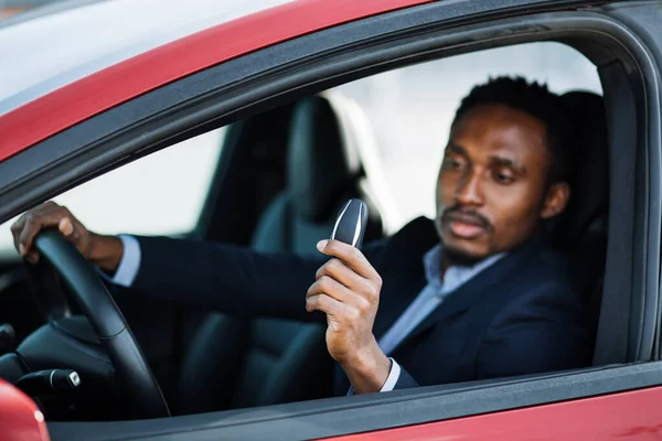 Afrikansk man sitter i ny elbil med nycklar i handen — Stockfoto