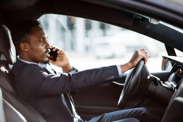Hombre de negocios africano hablando en el móvil mientras conduce el coche — Foto de Stock
