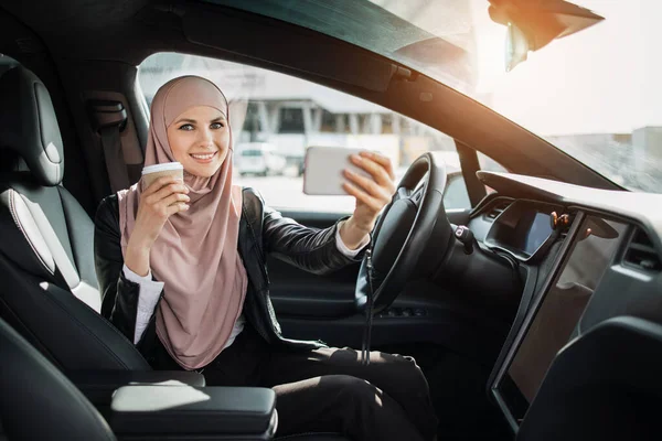 Femme en hijab ayant appel vidéo sur mobile à l'intérieur de la voiture — Photo