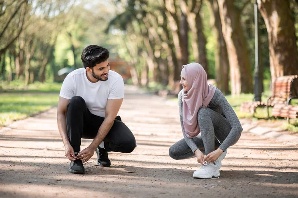 Hombre y mujer árabes atando cordones en zapatillas deportivas — Foto de Stock