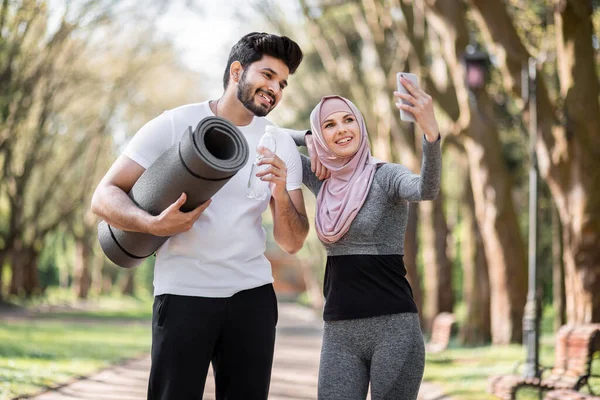 Casal muçulmano em roupas esportivas usando smartphone para selfie — Fotografia de Stock