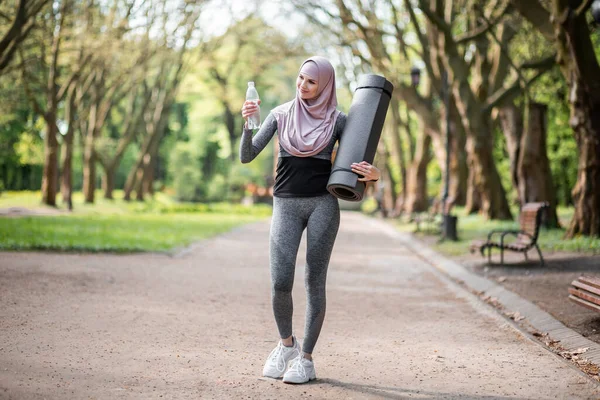 Mujer en hijab de pie en el parque con botella de agua — Foto de Stock