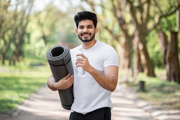在公园里穿着运动服笑着喝着水的阿拉伯男子 — 图库照片