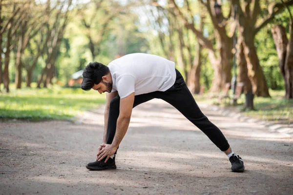 健康的穆斯林小伙子在公园跑步前伸展身体 — 图库照片