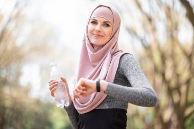 Parkta eğitim görürken tesettürlü kadın akıllı saat kullanıyor