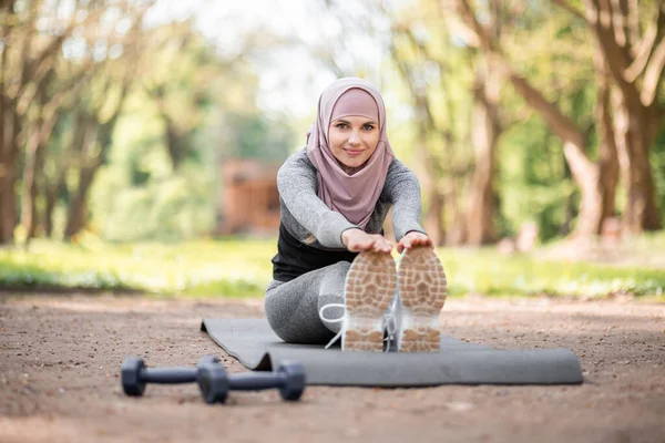 Mujer en hijab estirando el cuerpo en el parque de verano — Foto de Stock