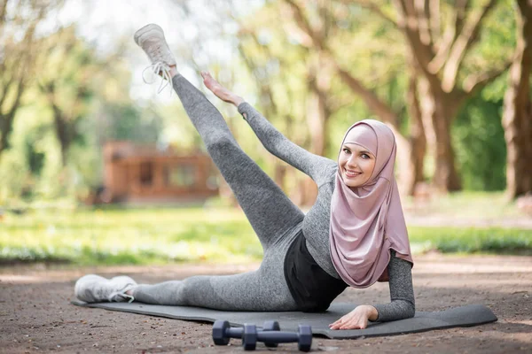 Mujer musulmana entrenando en esterilla de yoga en el parque de verano — Foto de Stock