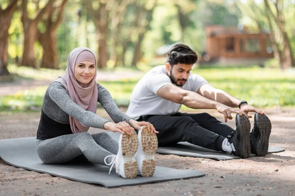 身穿运动服的穆斯林夫妇在户外伸腿 — 图库照片