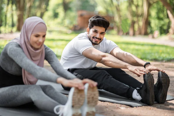 在室外瑜伽垫上热身的阿拉伯男女 — 图库照片