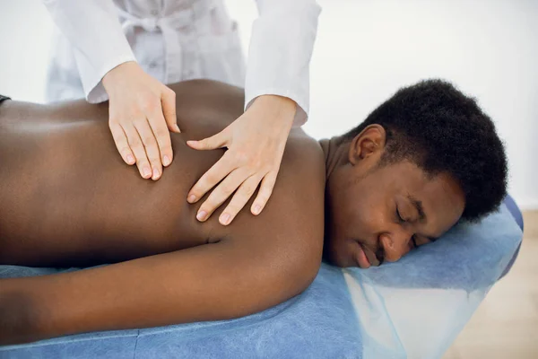 Close up of handsome young naked african man getting back massage