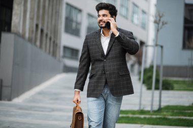 Arap girişimci sokakta yürüyor ve cep telefonuyla konuşuyor